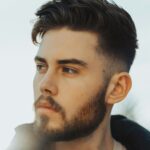 Homme debout en extérieur avec des cheveux foncés portant un taper fade et un dessus texturé
