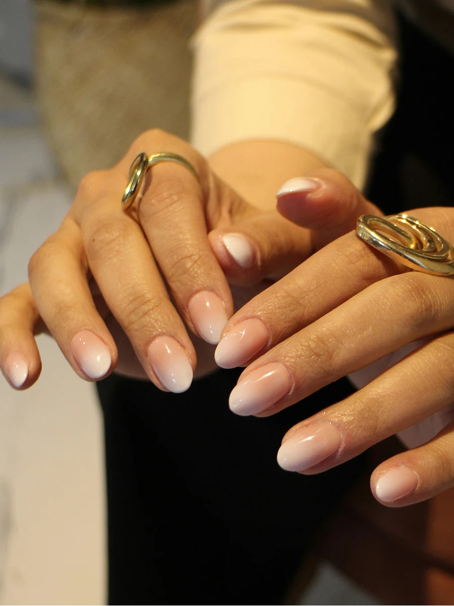 Gros plan d’une manucure Shellac ombrée dans des tons nude classiques, juste après la pose en salon