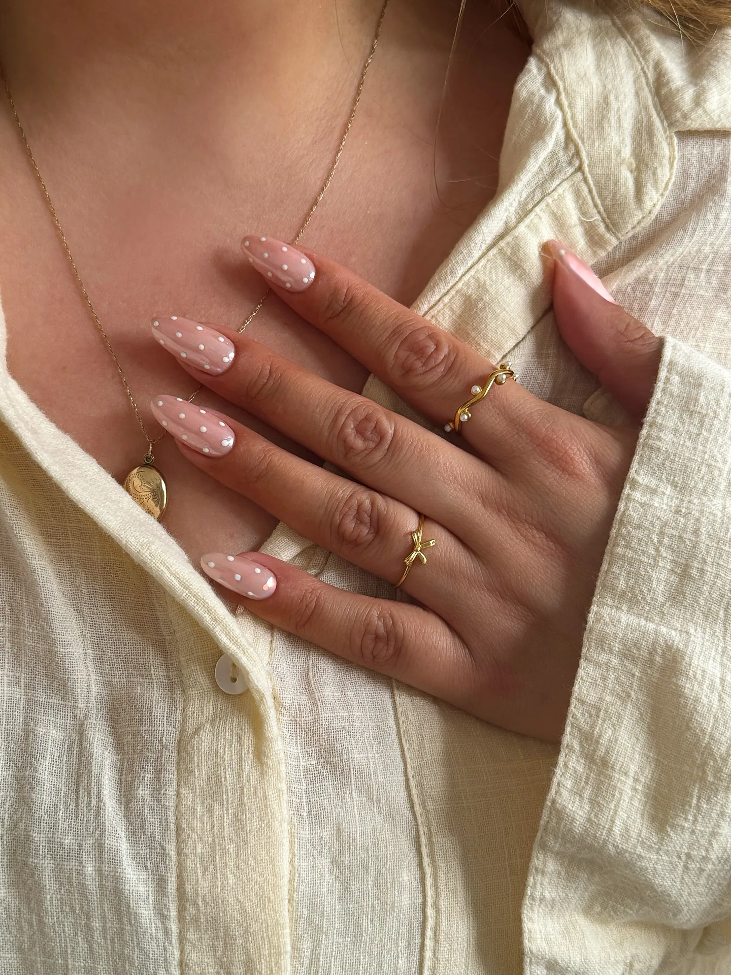 Ongles en amande sur base rose transparente, parsemés de micro-pois blancs régulièrement répartis.