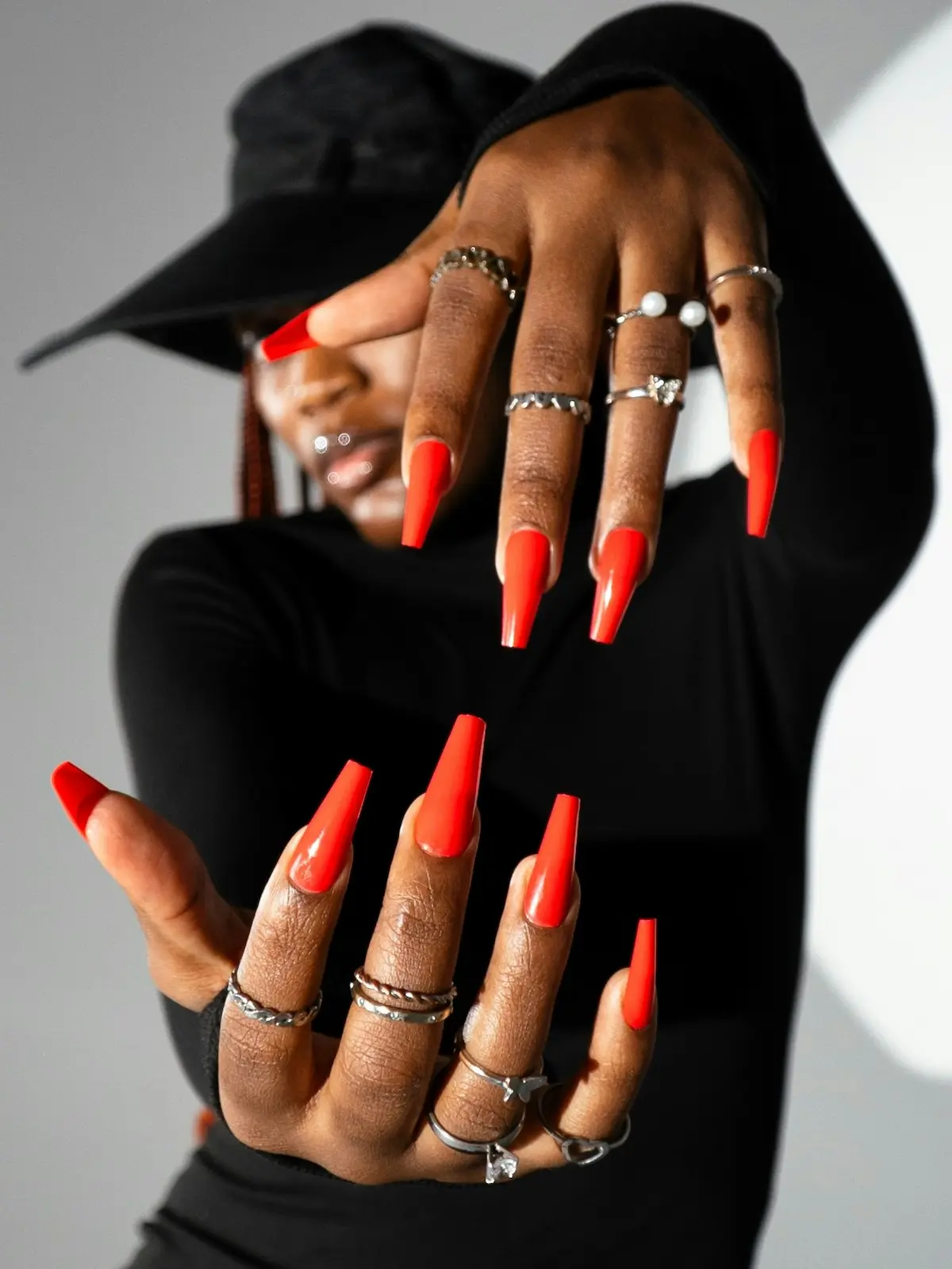 Une femme présente ses mains manucurées face à l'objectif, avec des ongles en résine orange vif en forme de ballerine