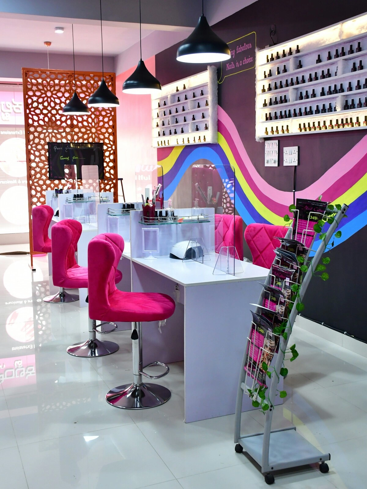 Intérieur d'un bar à ongles avec des plans de travail blancs propres et nets, des fauteuils en velours rose et un mur violet