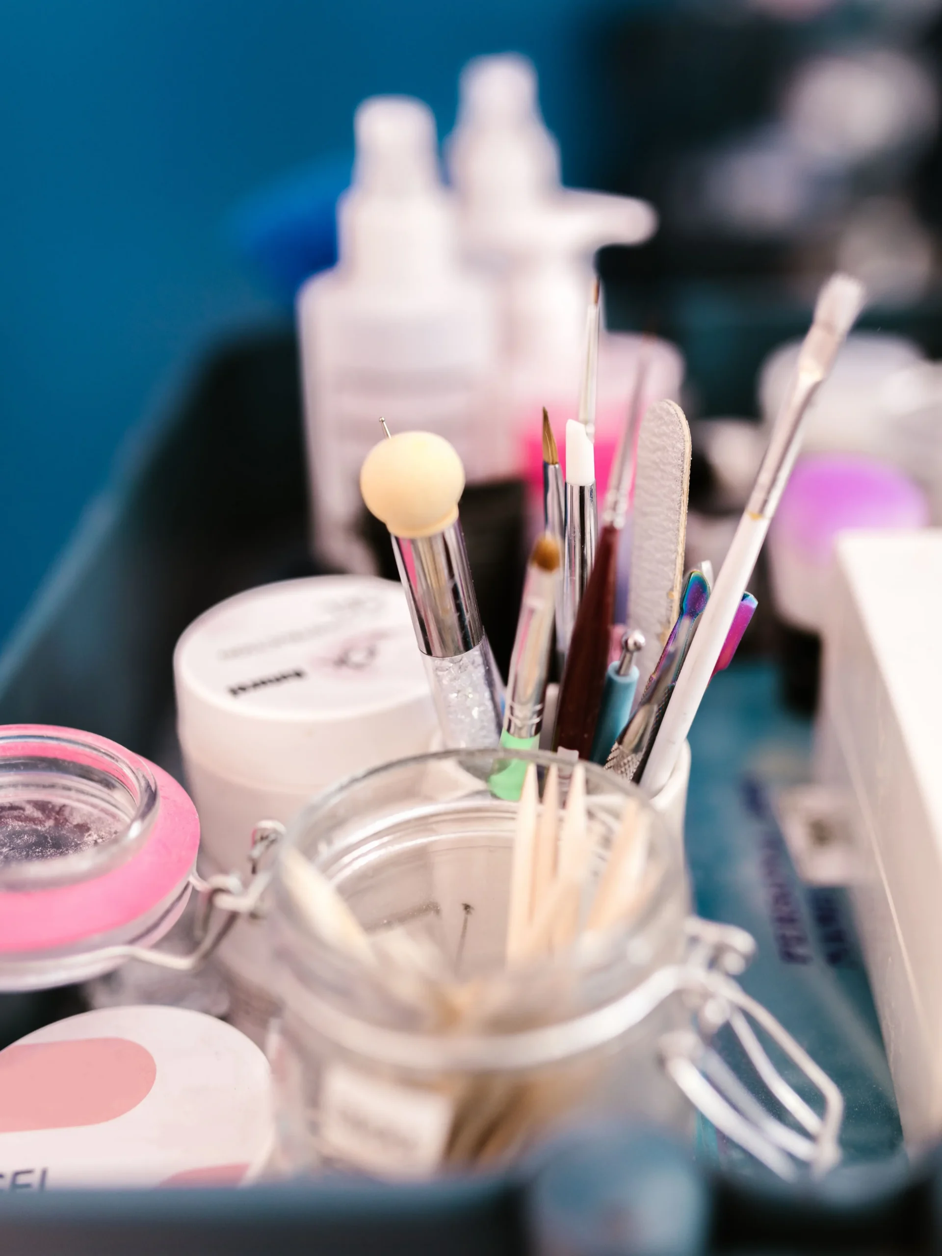 Gros plan sur le poste de travail d'une prothésiste ongulaire en salon, avec outils de manucure, pinceaux et produits