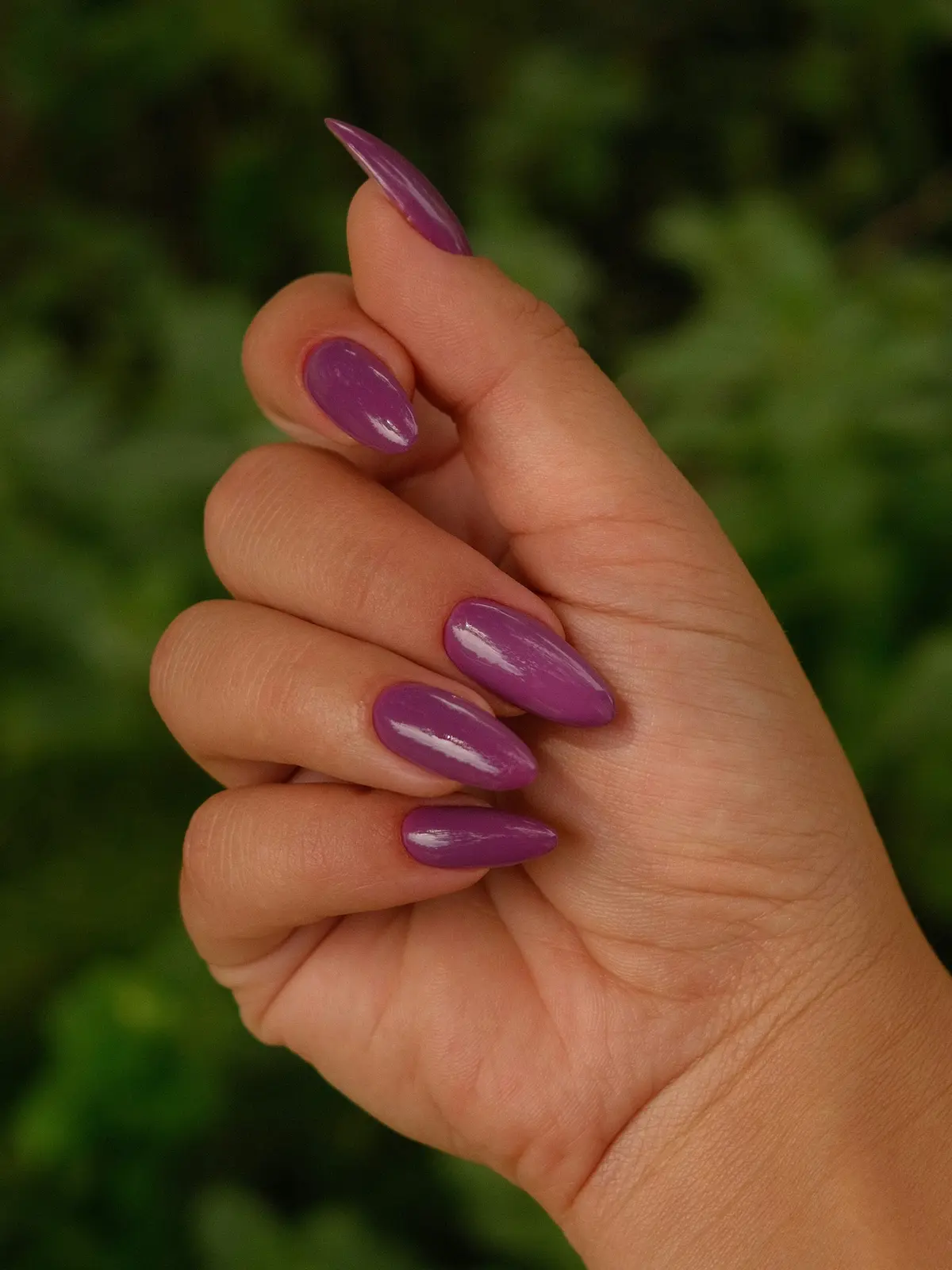 Gros plan sur la main d'une femme avec des ongles en résine violets en forme d'amande