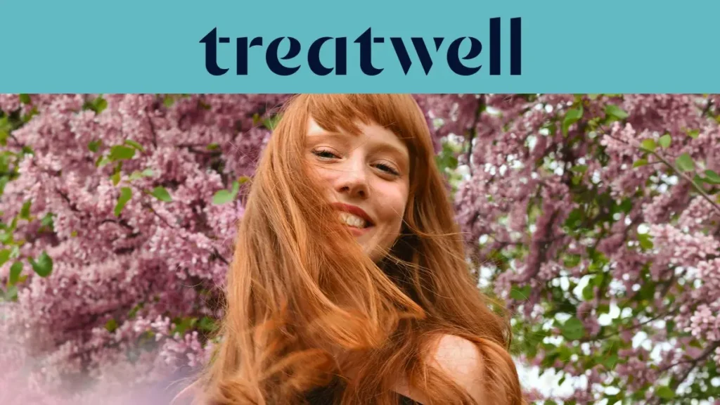 Portrait en gros plan d'une jeune femme rousse souriante avec une frange, dont les cheveux bougent au vent devant un arrière-plan de fleurs de lilas roses. Un bandeau bleu clair en haut affiche le logo "Treatwell" en bleu foncé.