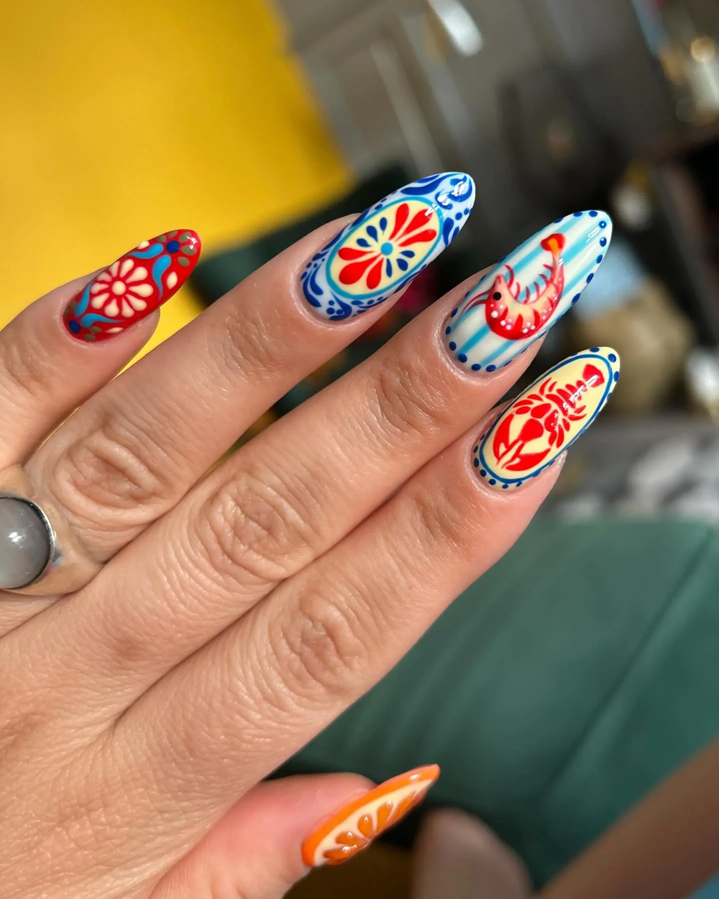 Nail art Destination nails sur des ongles en amande, motifs d'inspiration méditerranéenne en rouge, bleu et orange
