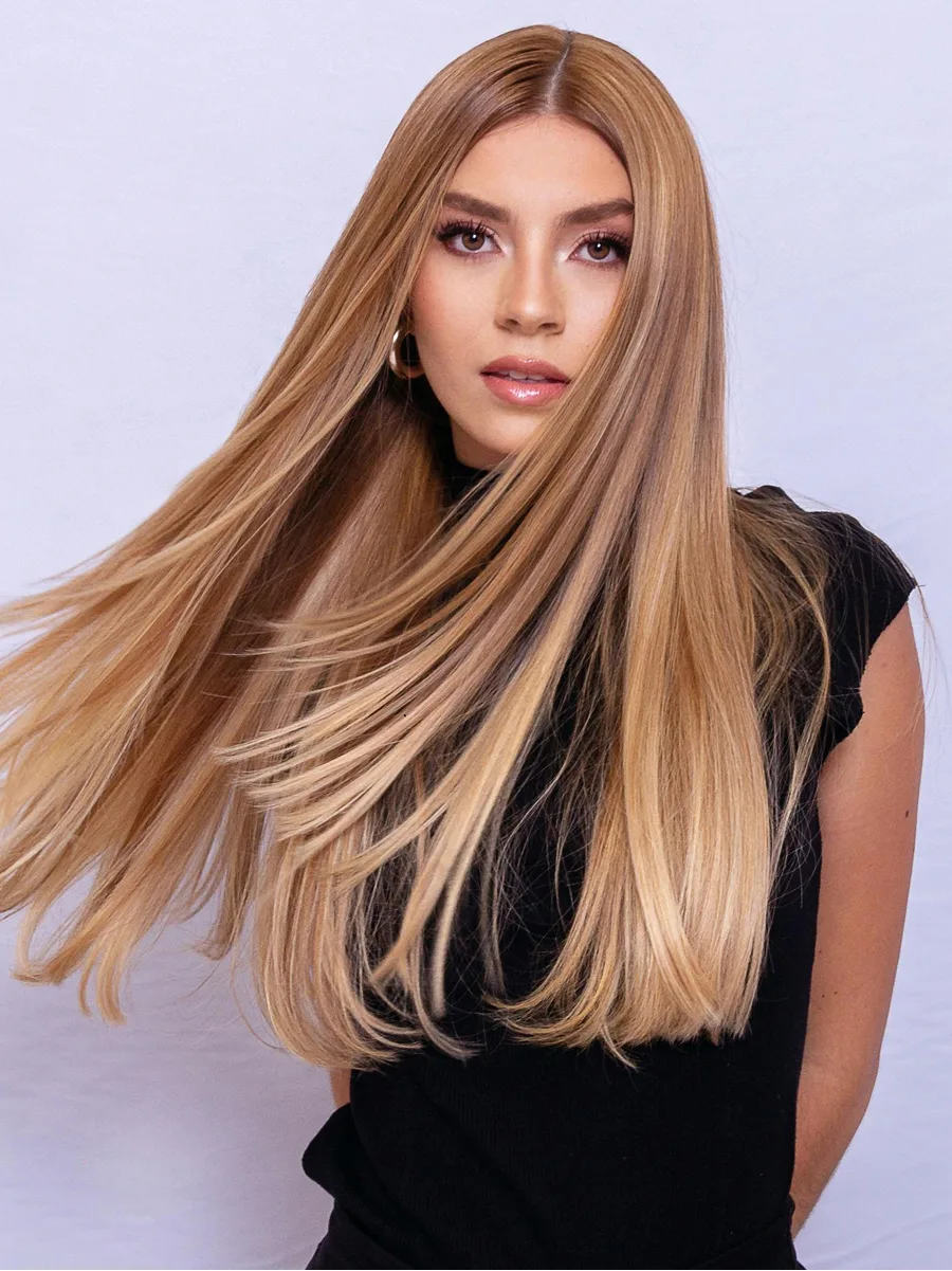 Portrait en studio d’une femme balançant ses longs cheveux blond caramel brillants