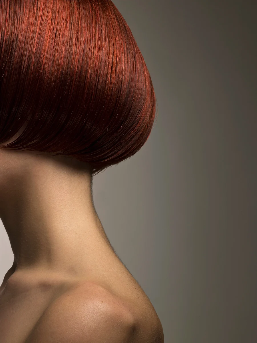Gros plan de profil de la tête d’une femme arborant un carré roux teint et brillant