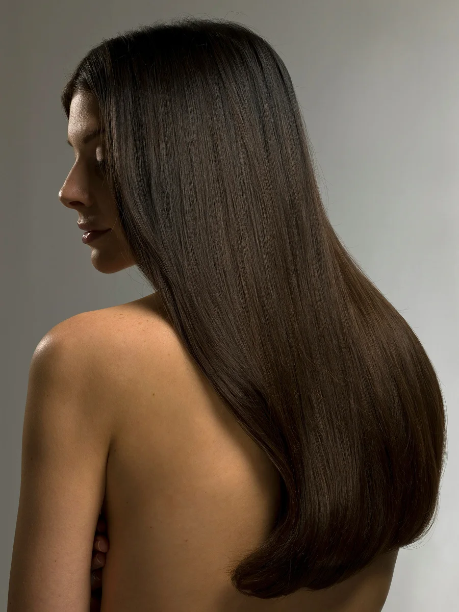 Portrait de profil en studio d’une femme aux longs cheveux bruns brillants