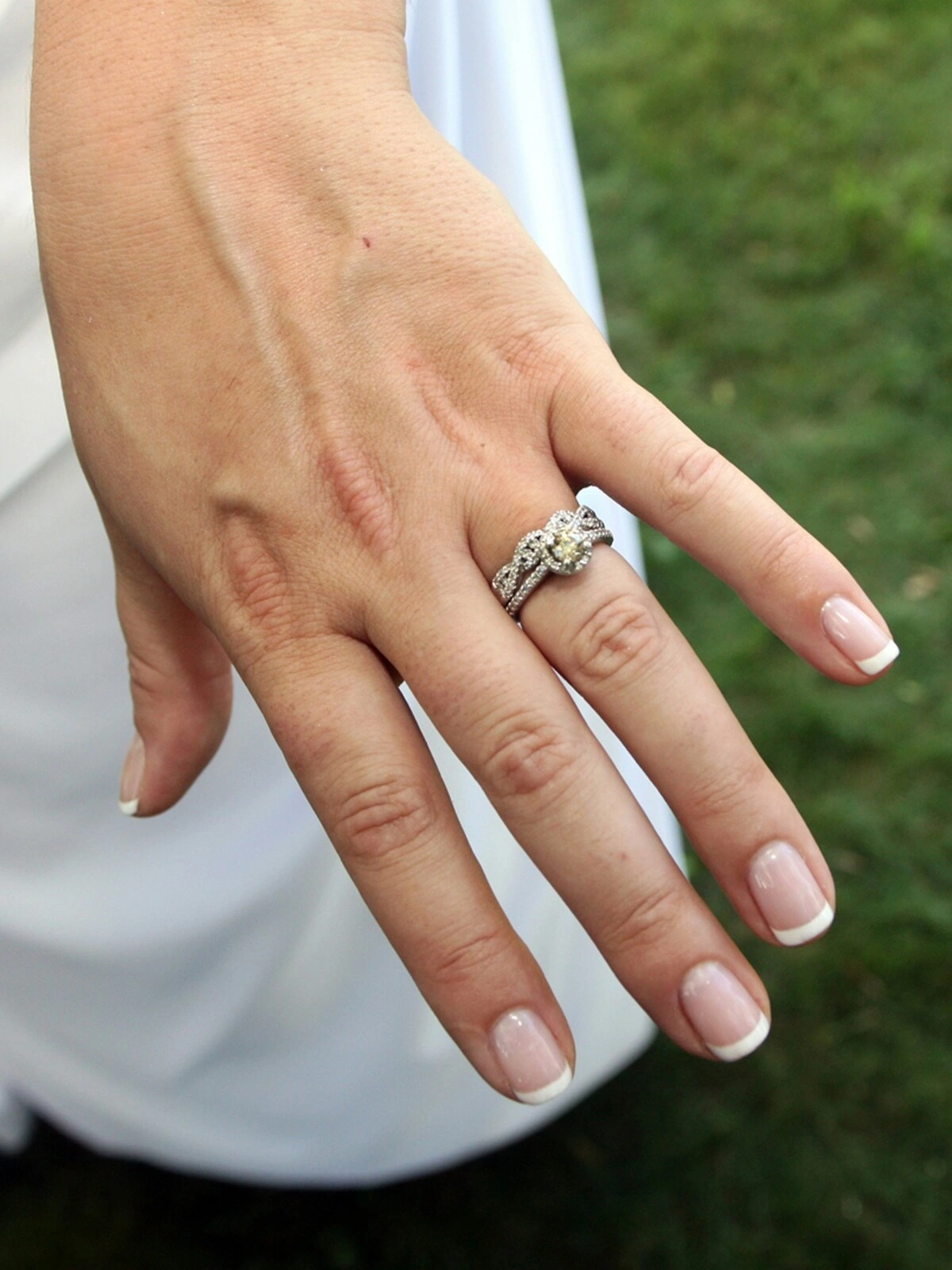 La main d'une femme arborant une jolie French manucure dans une association classique de nude et de blanc sur des ongles courts carrés-ovales
