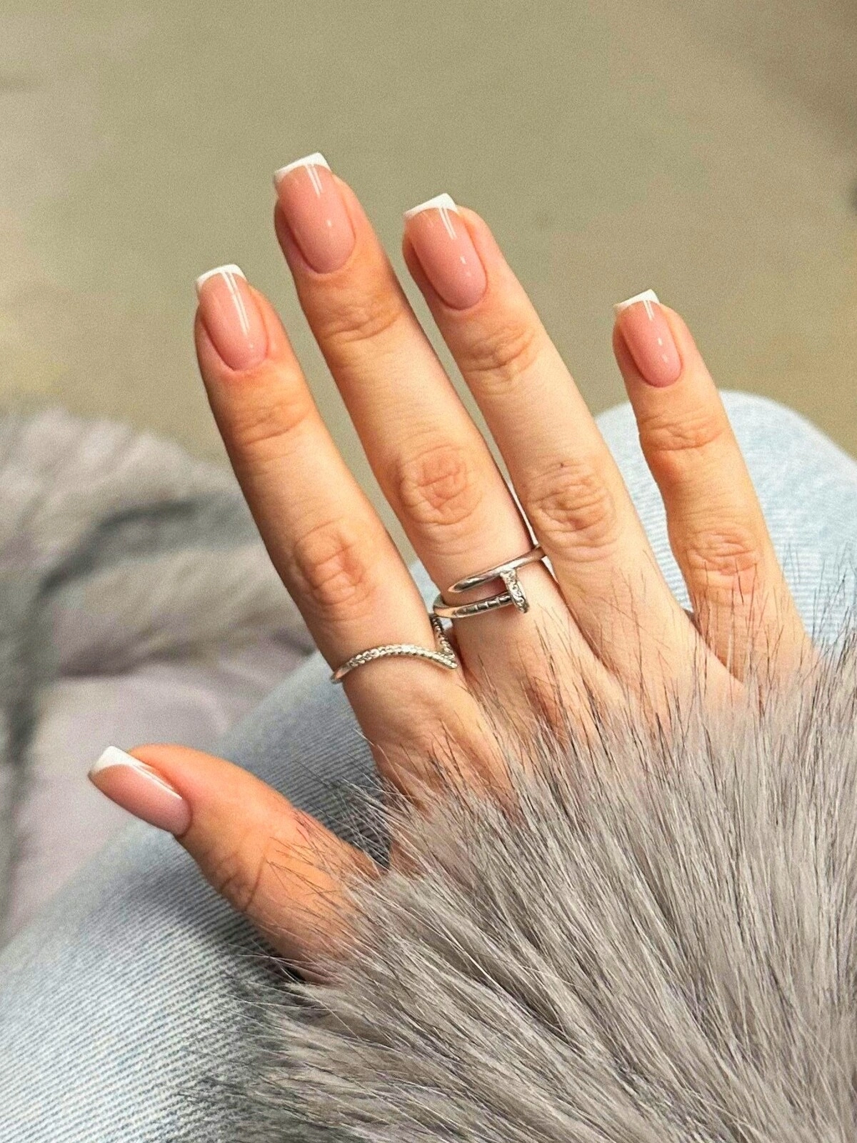 La main d'une femme arborant une French manucure aux micro-lignes sur des ongles carrés