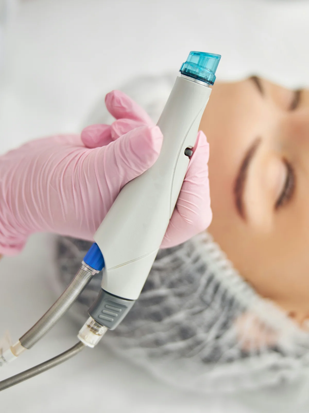 Gros plan d'un appareil Hydrafacial à embout en spirale tenu par une esthéticienne