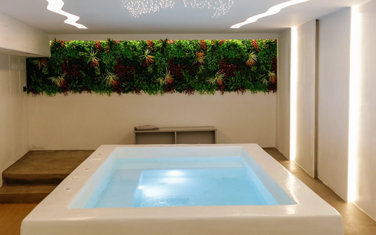 Le bassin d'hydrothérapie de Liana Spa Therapy à Naxos, éclairé en douceur de l'intérieur, sous un mur végétal coloré de plantes stabilisées et un plafond parsemé de minuscules étoiles lumineuses.