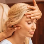 Gros plan sur une femme aux yeux fermés pendant un massage indien de la tête, une praticienne posant une main sur son front et massant sa nuque de l'autre